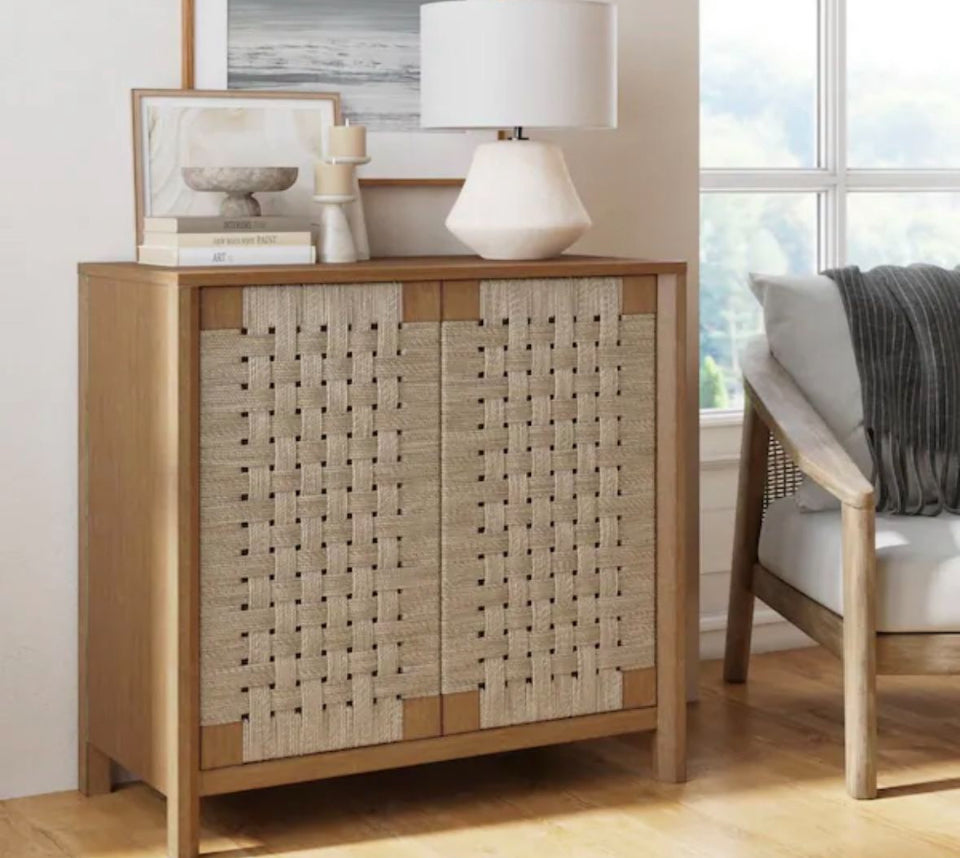 Nathan James Aerie rustic wood accent cabinet with light brown finish and woven seagrass doors in a boho living room setting