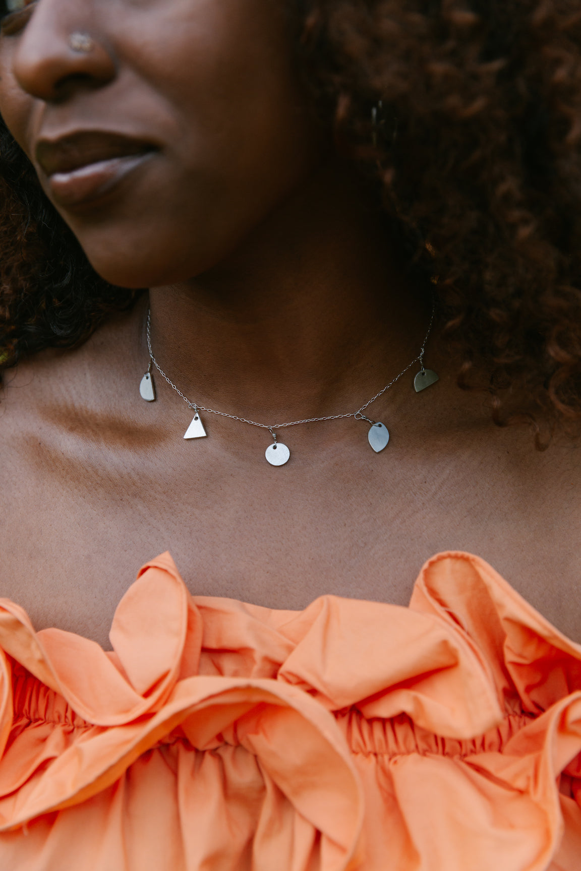 Ti Fom Necklace with upcycled aluminum pendants on sterling silver chain worn by woman in orange top