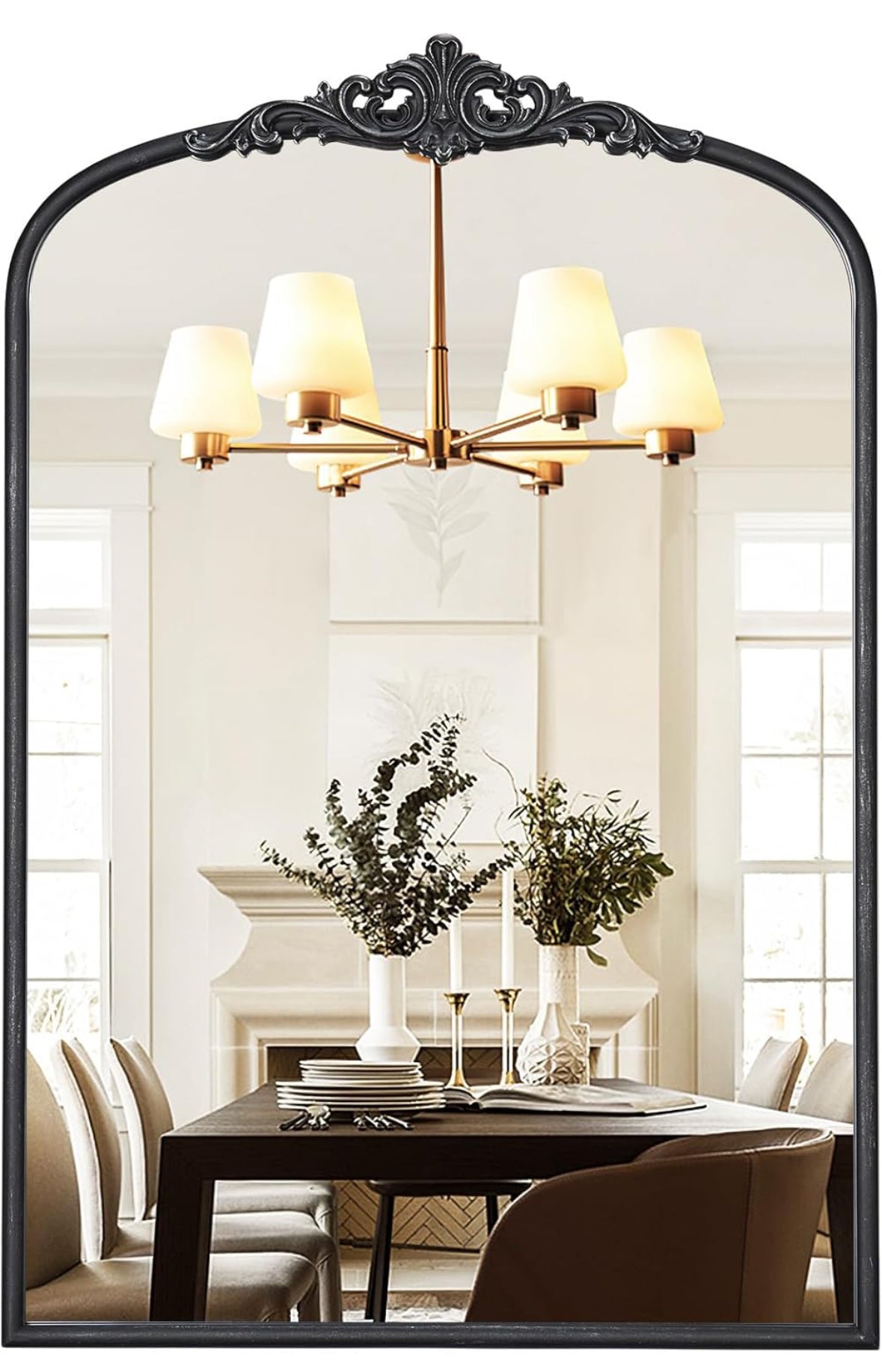 Arched antique wall mirror with ornate black metal frame reflecting elegant dining room.