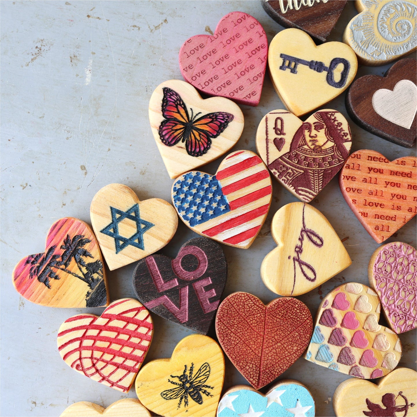 Handmade engraved wooden hearts with various designs including butterfly, American flag, love text, and key, crafted from reclaimed wood.