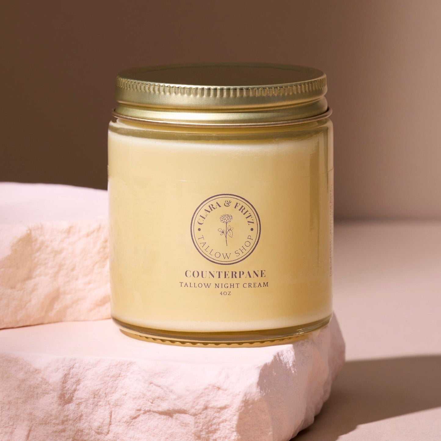 Counterpane Tallow Night Cream in glass jar with gold lid on stone surface for moisturizing and nourishing skin overnight