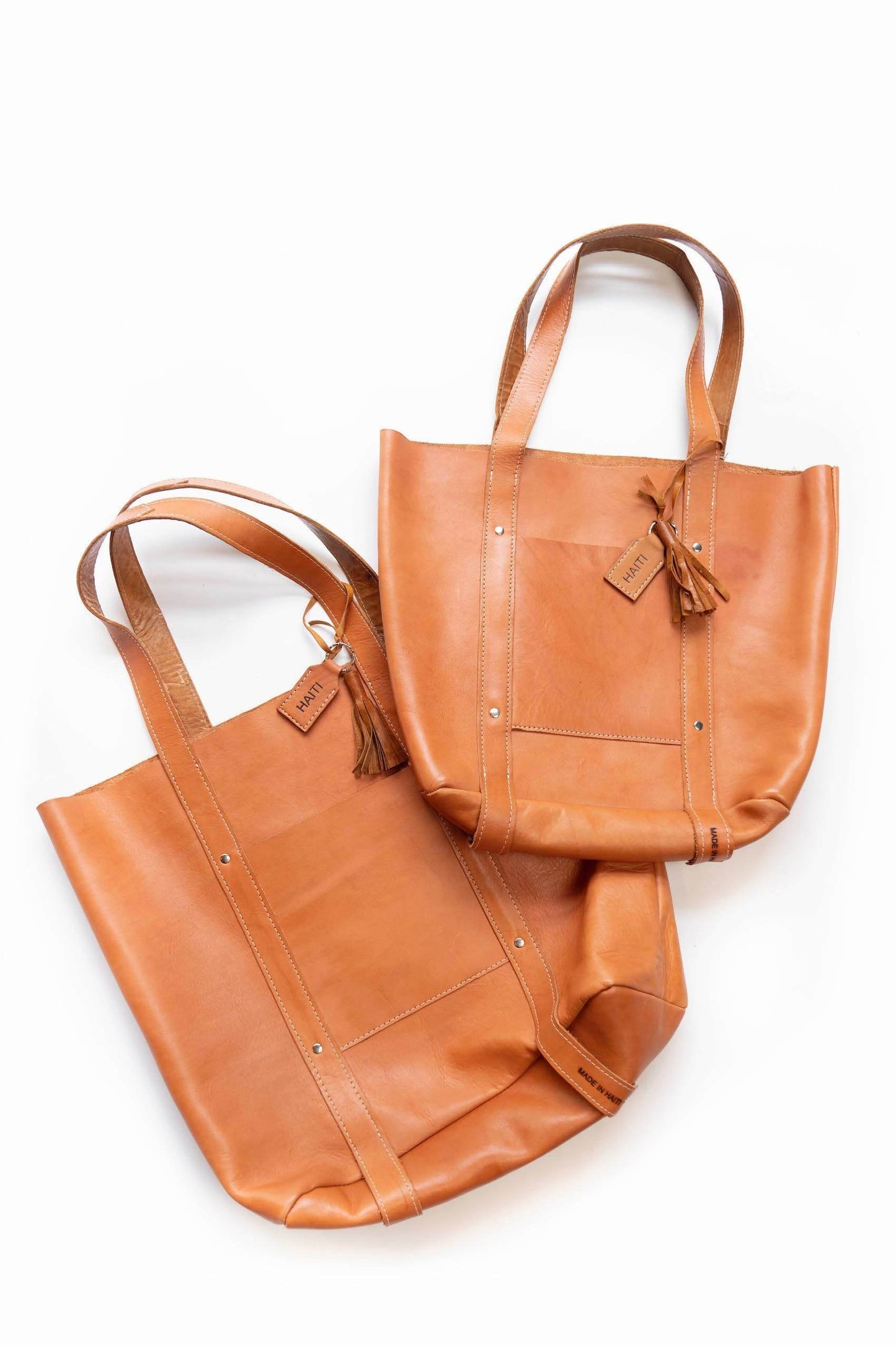 XL Raw Leather Tote bag in full-grain leather with detachable tassel and Haiti tag, featuring internal and external pockets, perfect for work, school, or travel.