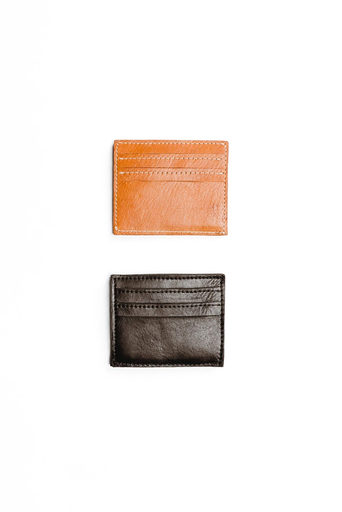 Two minimalist leather wallets, one tan and one black, with multiple card slots on a white background