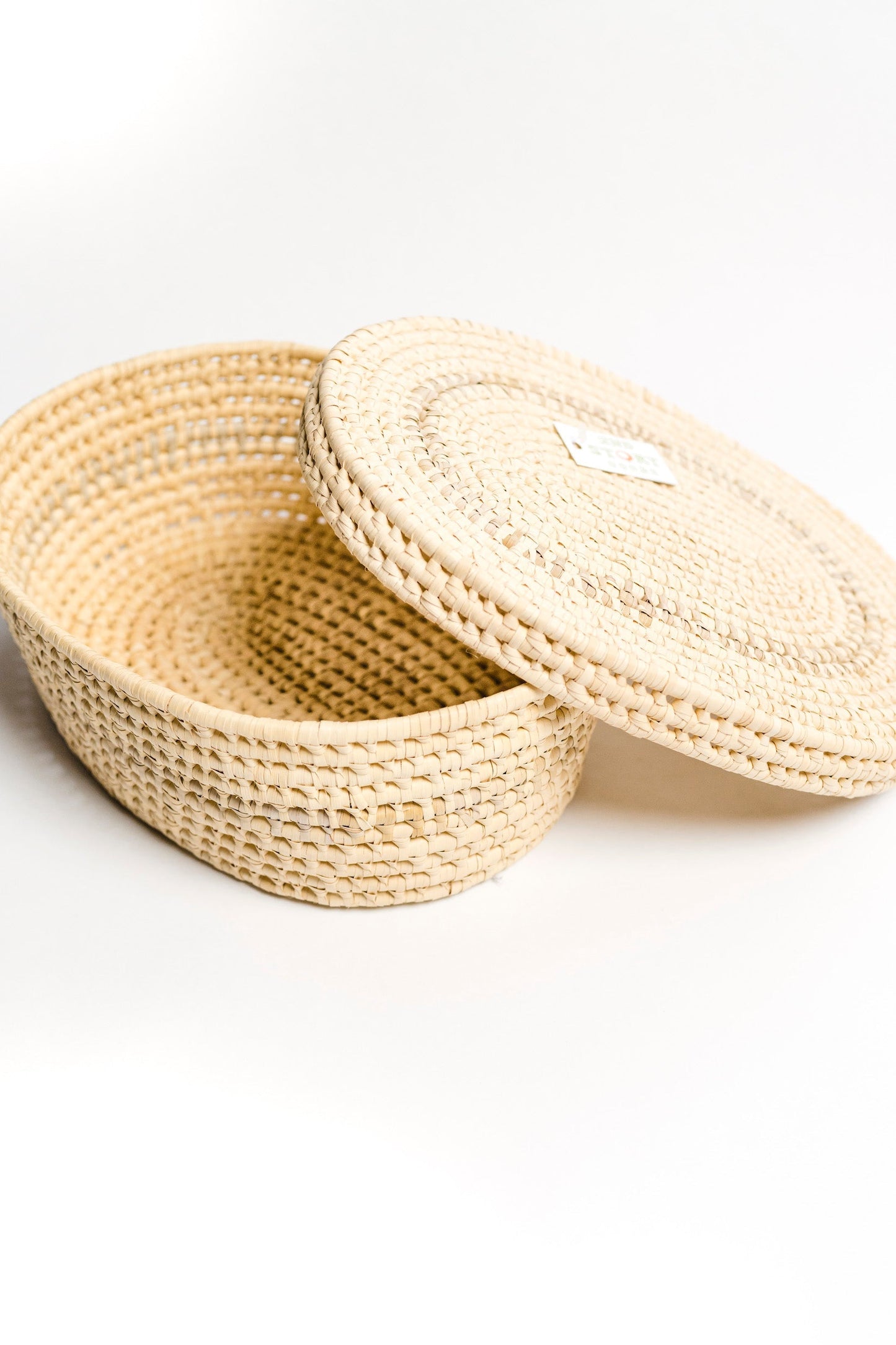 Oval woven basket with lid made from natural palm leaves for stylish storage