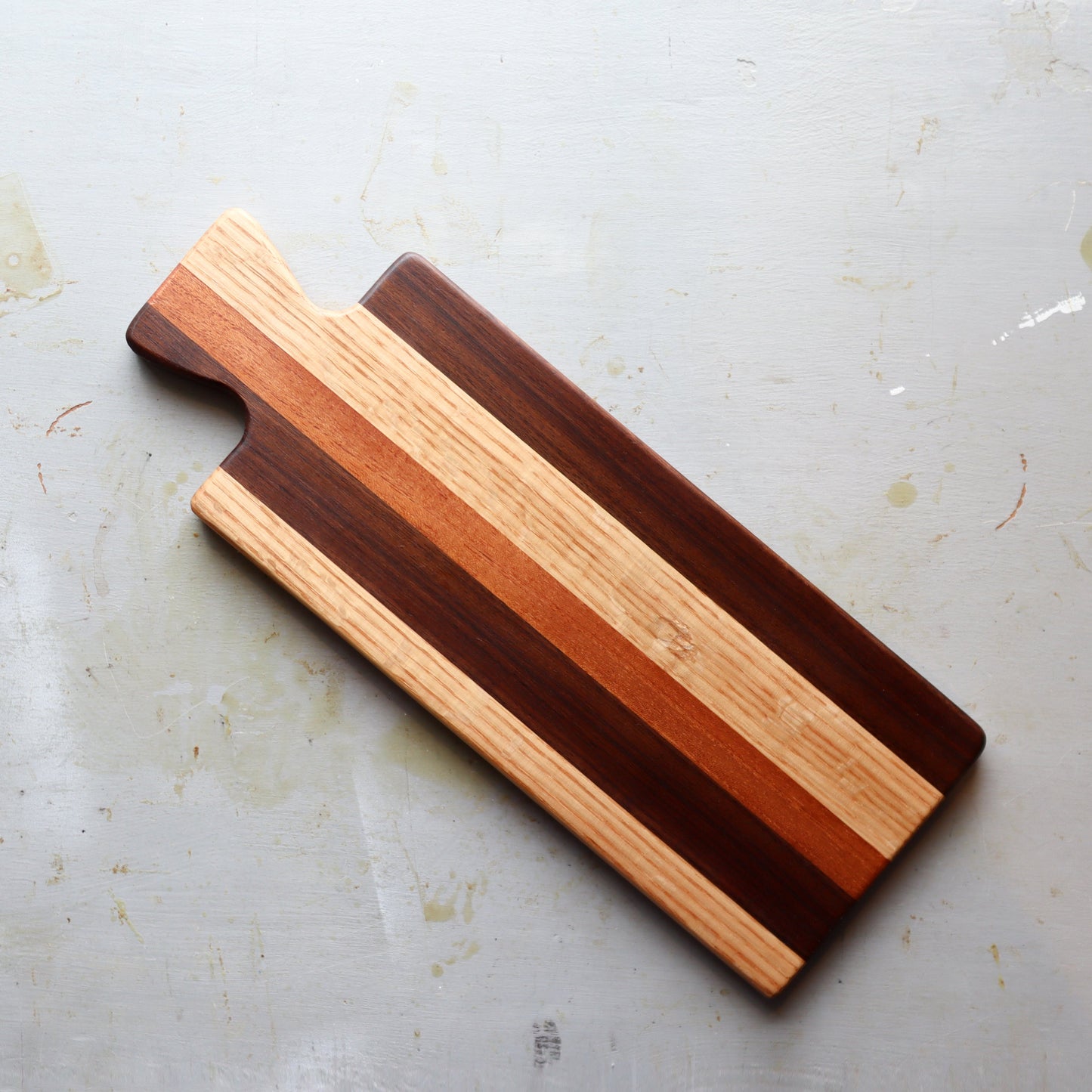 Handmade reclaimed hardwood charcuterie board with stub handle, featuring contrasting wood stripes and food-safe finish for serving meats and cheeses