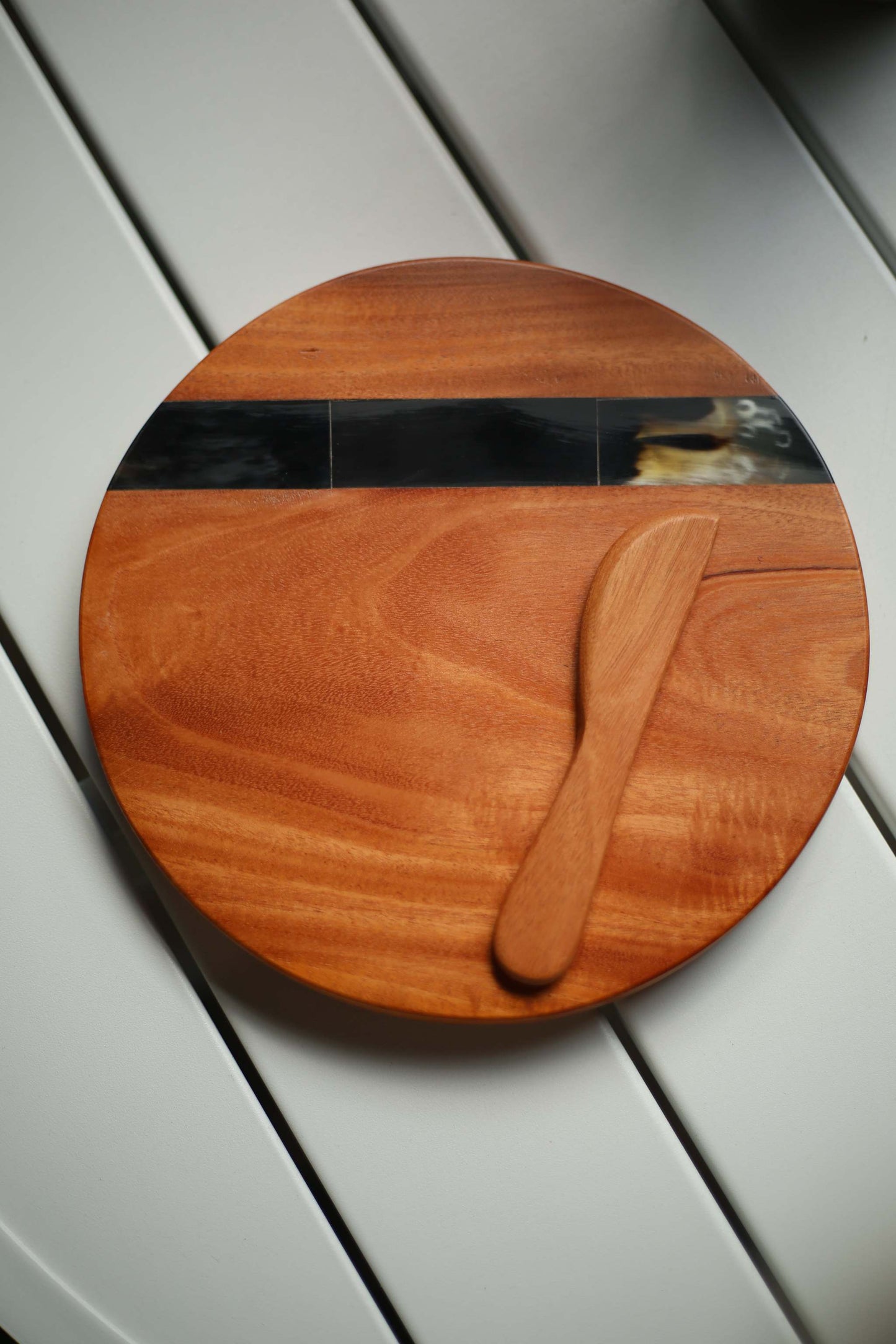 Round wooden cheese board with mosaic horn inlay and hand-carved wooden spreader knife