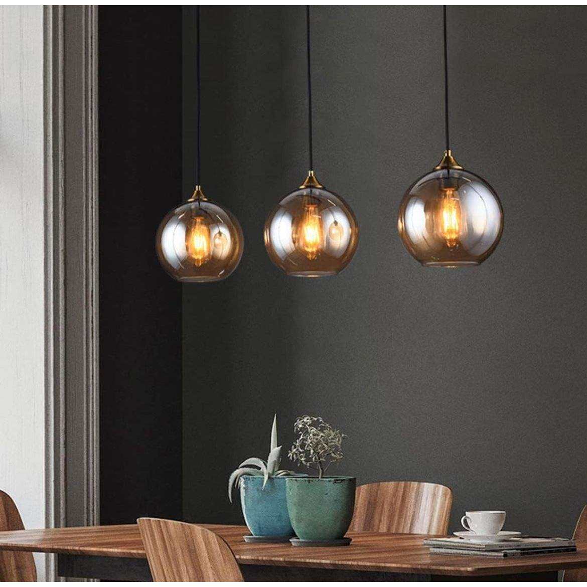 Vintage mid-century amber glass pendant light fixtures hanging over wooden dining table