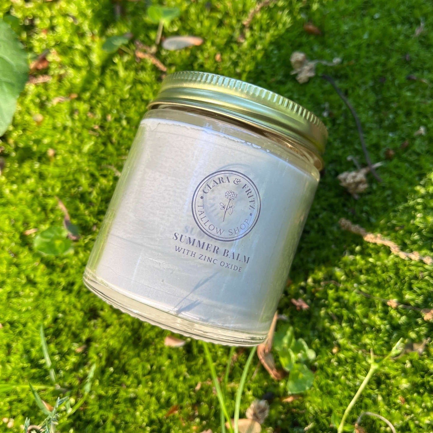 Glass jar of Summer Balm for Body with zinc oxide on green moss background
