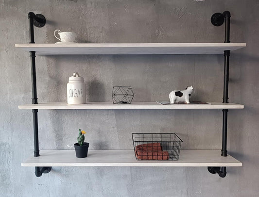 Rustic white wooden floating bookshelf shelves with black industrial metal pipe frame mounted on a gray wall, holding decorative items.