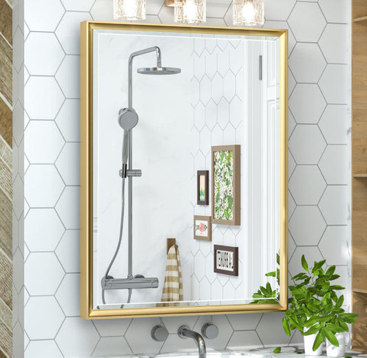Recessed medicine cabinet with gold metal frame and beveled mirror edges mounted on bathroom wall