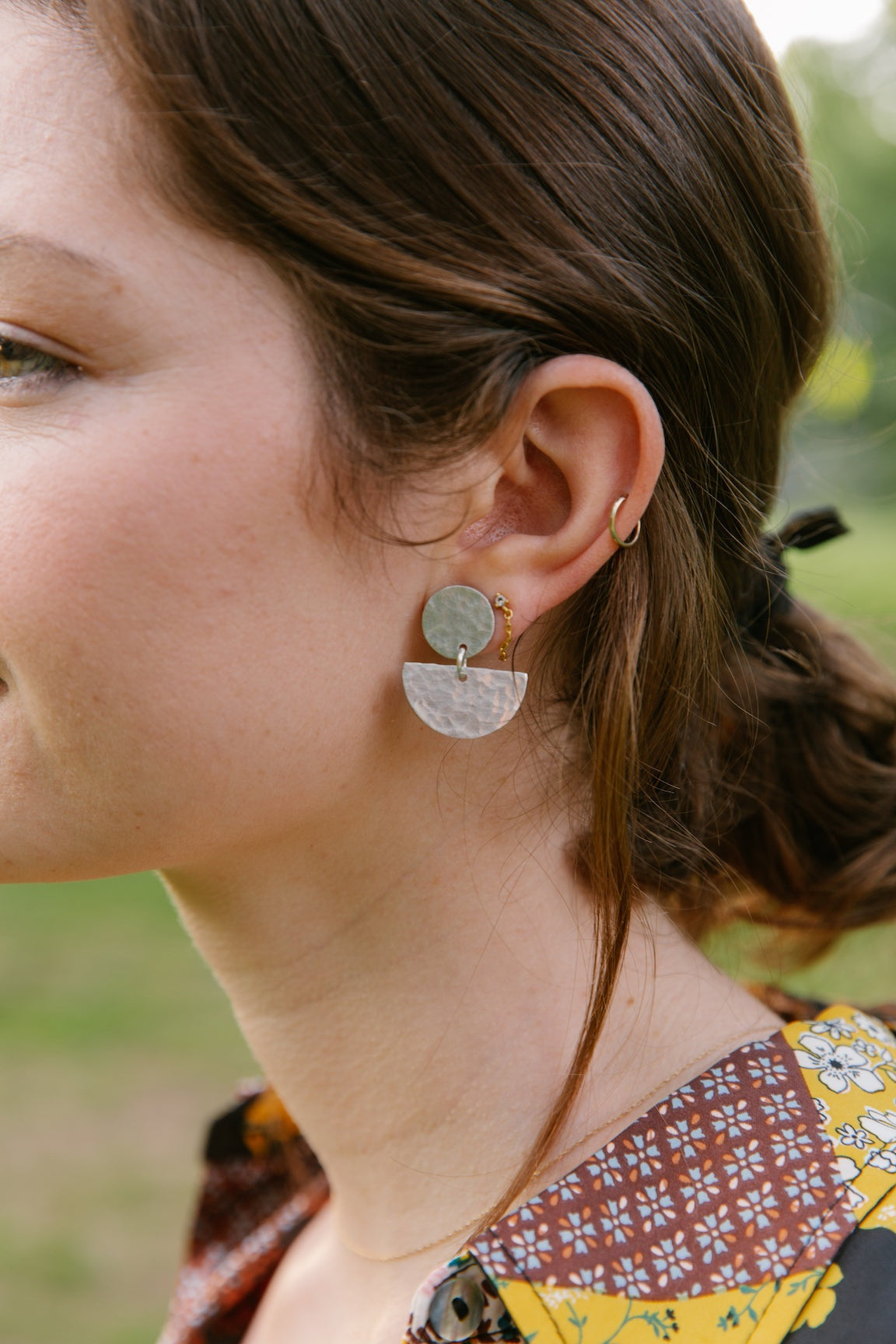 Close-up of a woman wearing Luna Earring with silver-plated brass stud and upcycled aluminum pendant
