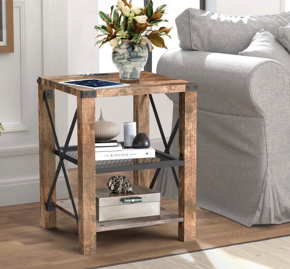 Eidelweiss Tall End Table with wood finish, metal frame, two USB ports, power outlets, and three storage shelves next to a gray sofa