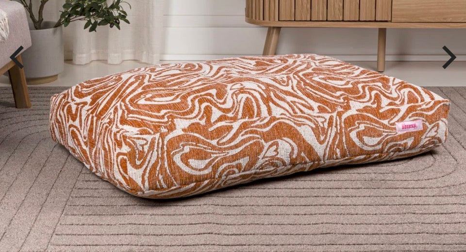 Maya Modern Pet Bed with washable cover and bold orange swirl pattern placed on a grey rug in modern room