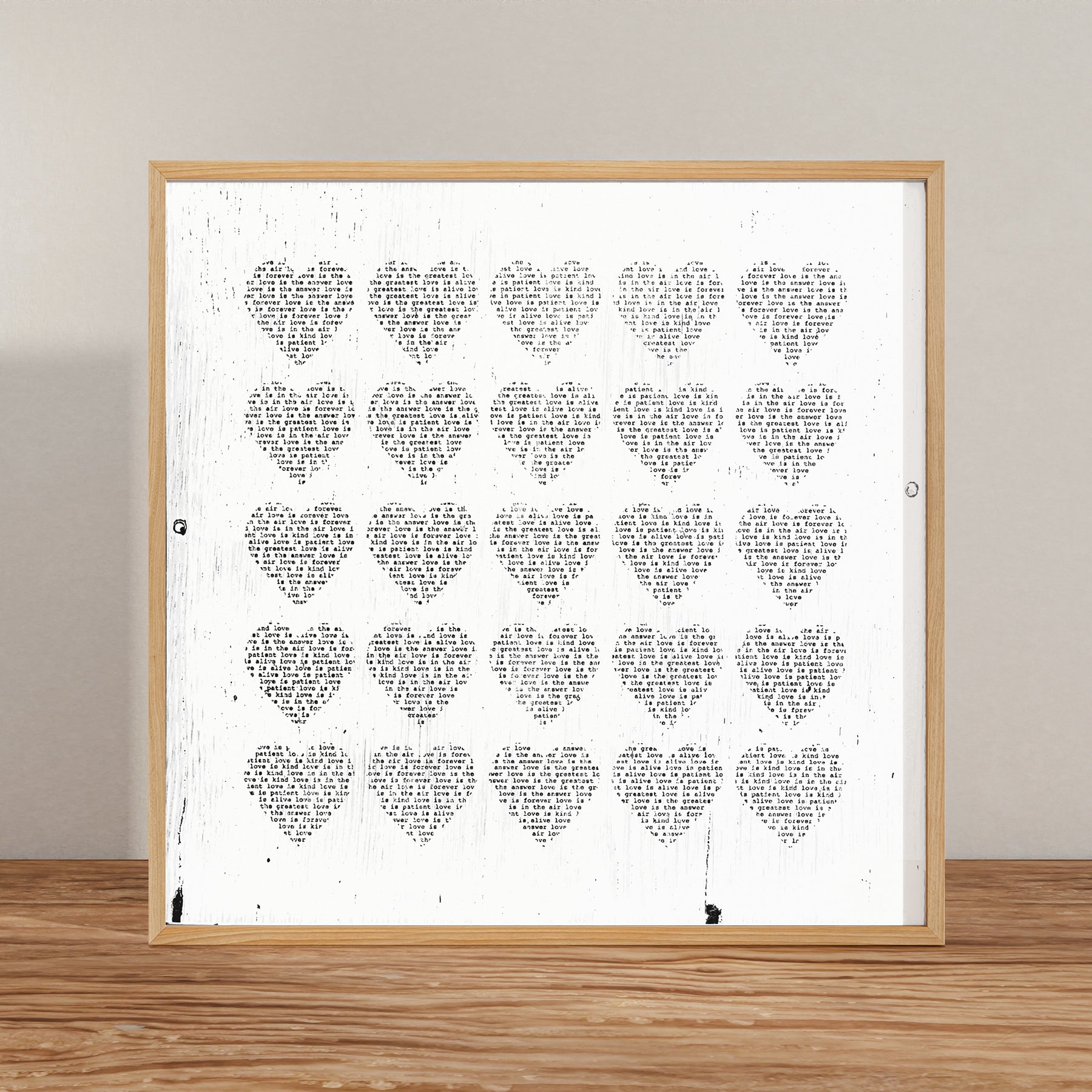 Love Is... Art Prints featuring typewriter-style text in heart shapes on a white 12x12 inch archival paper print with wooden frame