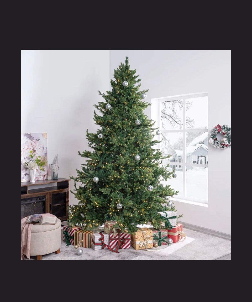 Pre-lit green full artificial pine Christmas tree with warm white LED lights and realistic layered branches in a modern living room.