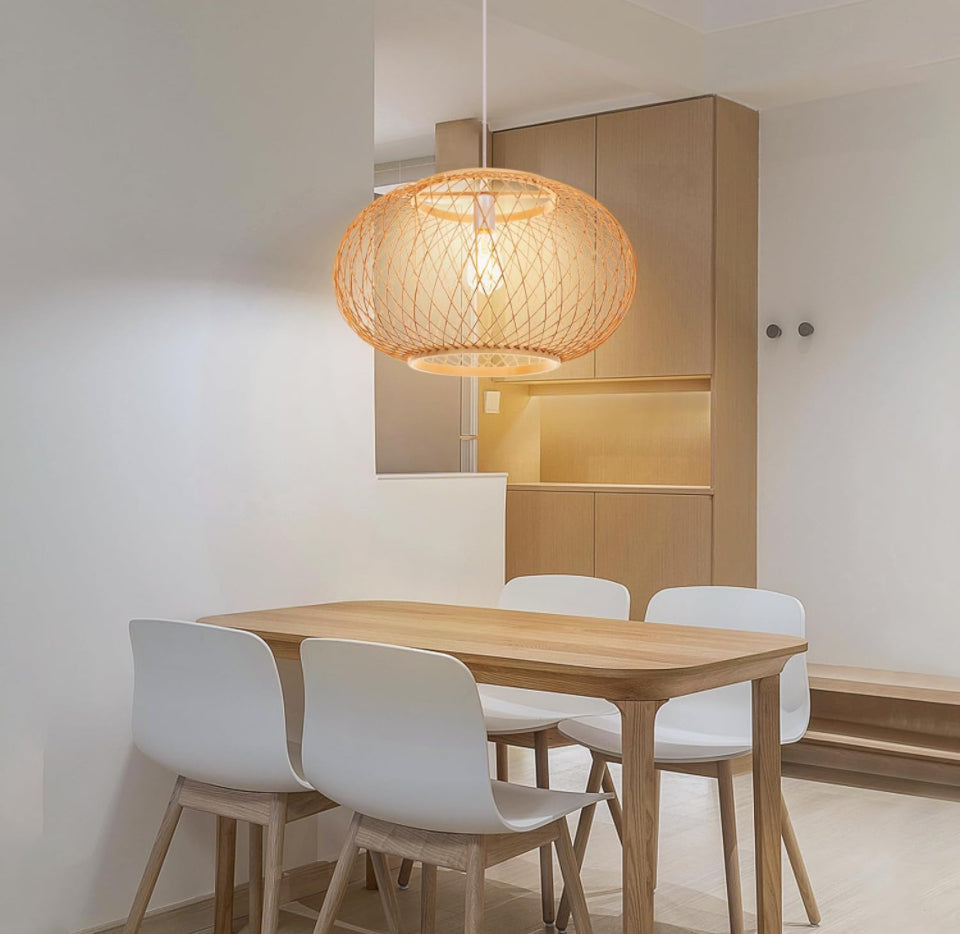 Bamboo pendant light with boho hand-woven oval lampshade hanging over dining table.