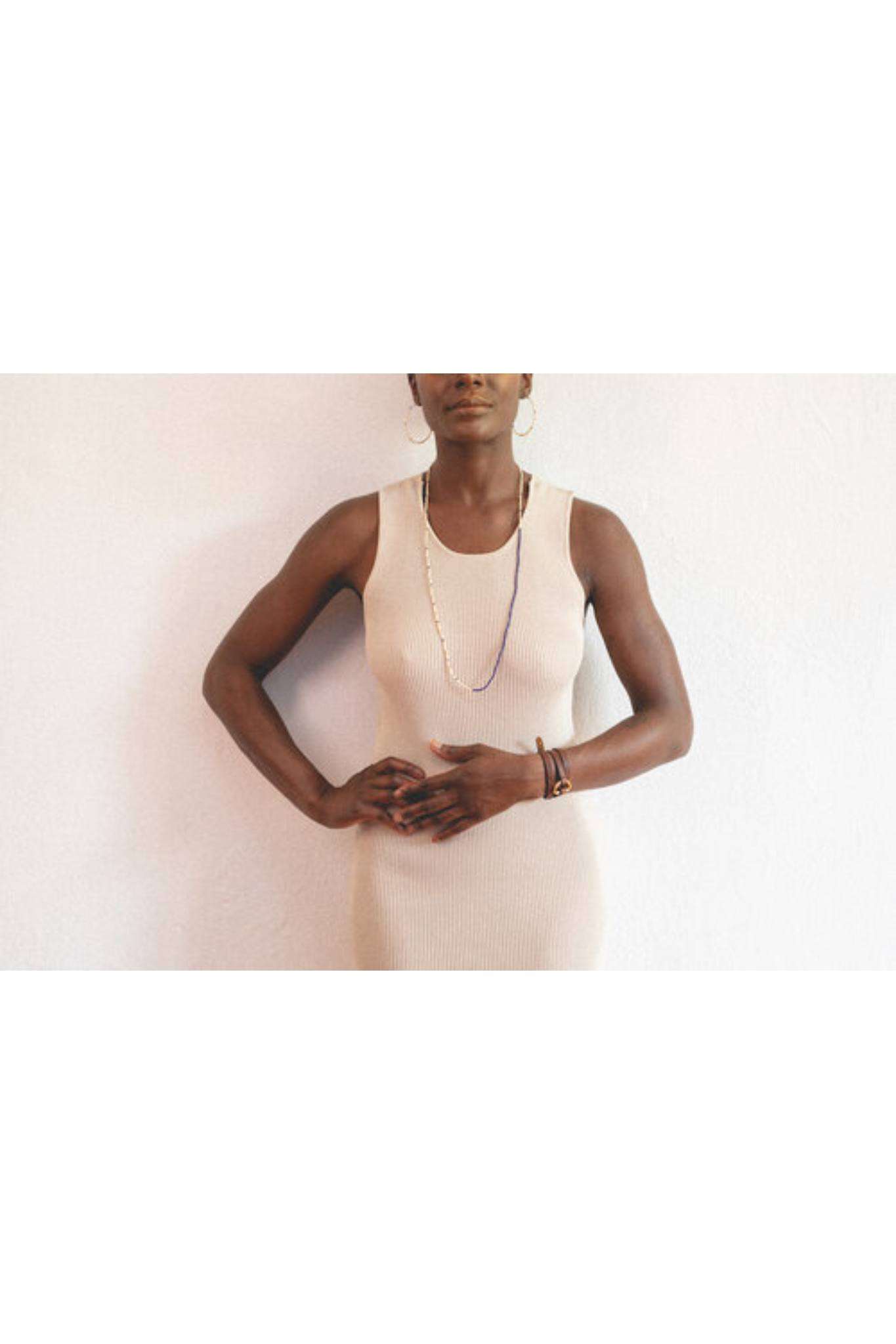 Woman wearing a black and cream glass bead Cafe Necklace with a simple, lightweight design over a beige sleeveless dress.