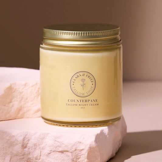 Counterpane Tallow Night Cream in glass jar with gold lid on stone surface for moisturizing and nourishing skin overnight