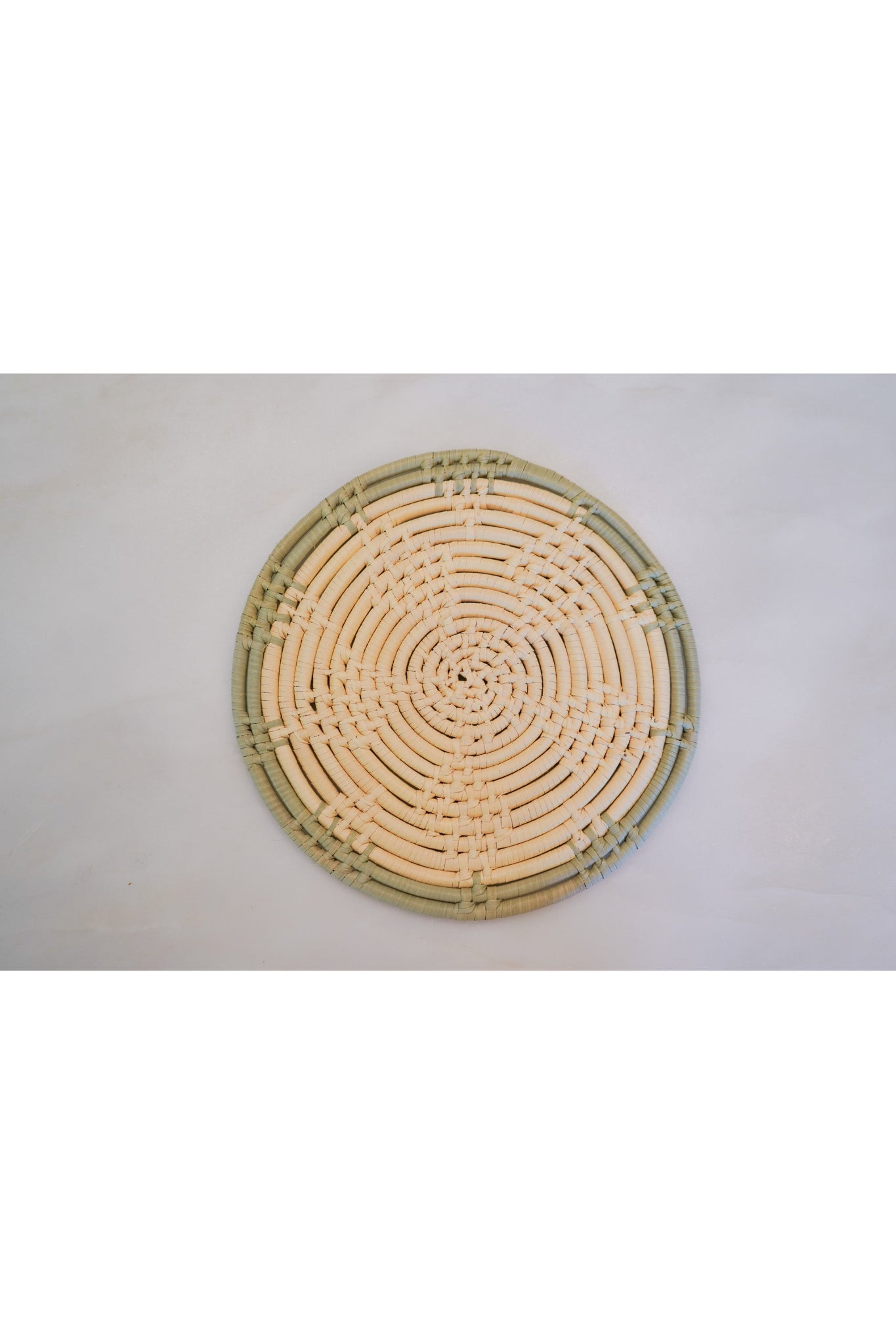 Round 8 inch woven trivet with sage green trim made from natural palm leaves.