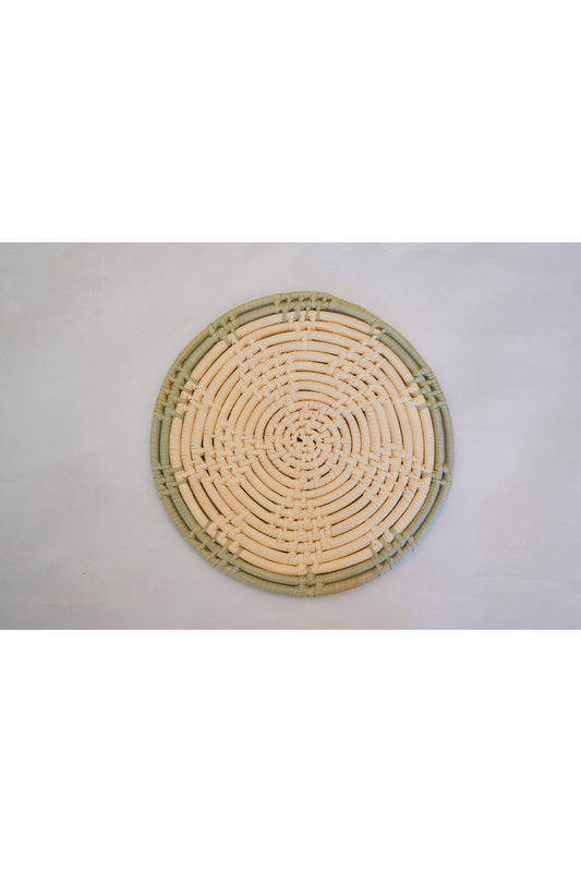 Round 8 inch woven trivet with sage green trim made from natural palm leaves.