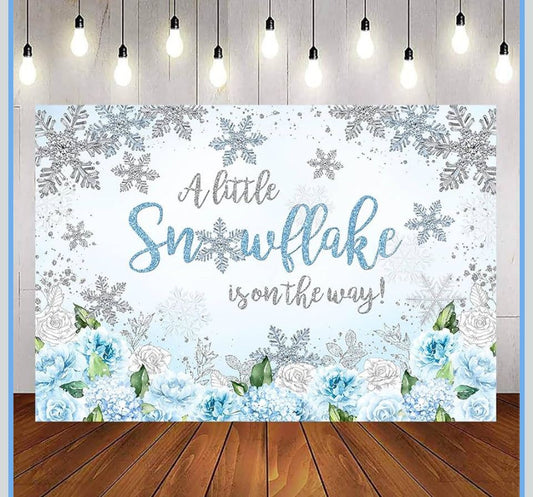 Blue and silver snowflake baby shower backdrop with "A little snowflake is on the way" text and floral design