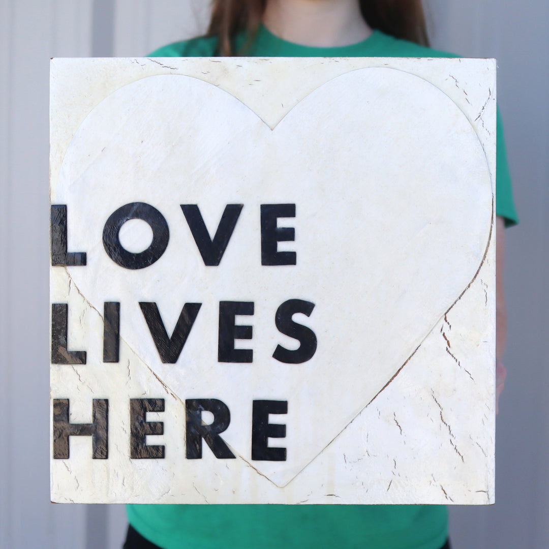 Handmade Love Lives Here artwork on reclaimed piano wood with textured acrylic paint and decoupage lettering.