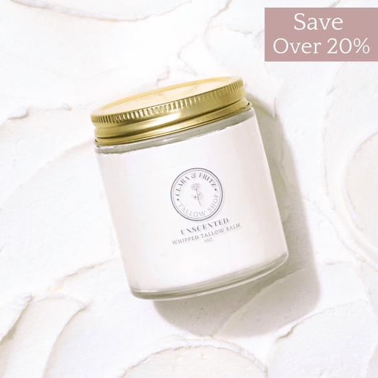 Glass jar of Clara & Fritz Unscented Whipped Tallow Balm moisturizer with gold lid on textured white background, promoting over 20% savings.