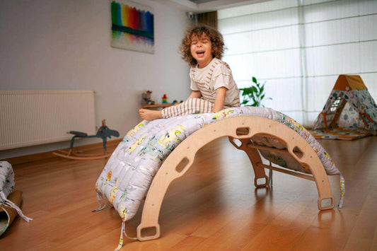 Child playing on an XL Climbing Arch/Rocker with a colorful map pattern cushion in a bright playroom