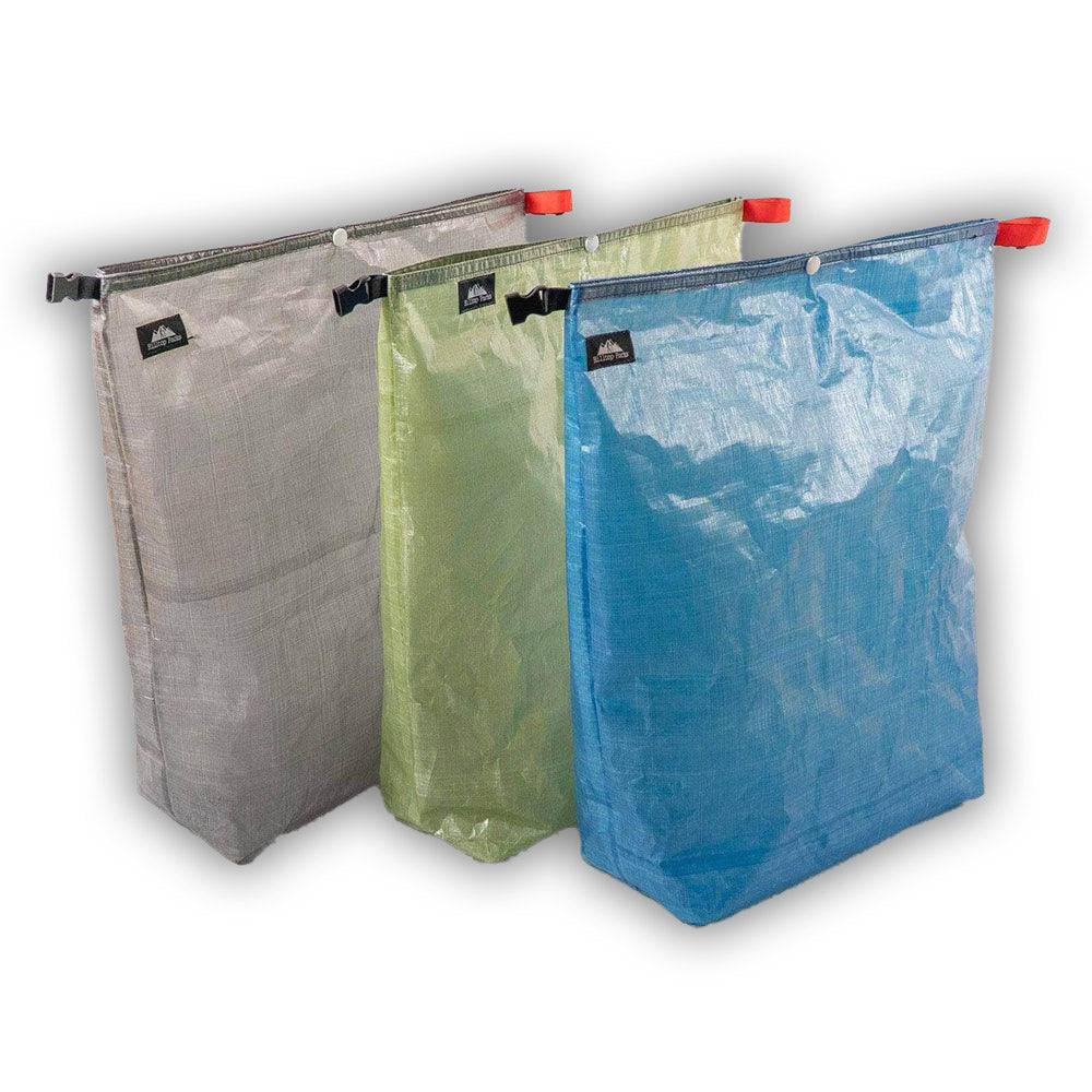 Set of three ultralight Dyneema fabric food bags in gray, green, and blue for backpacking and camping.