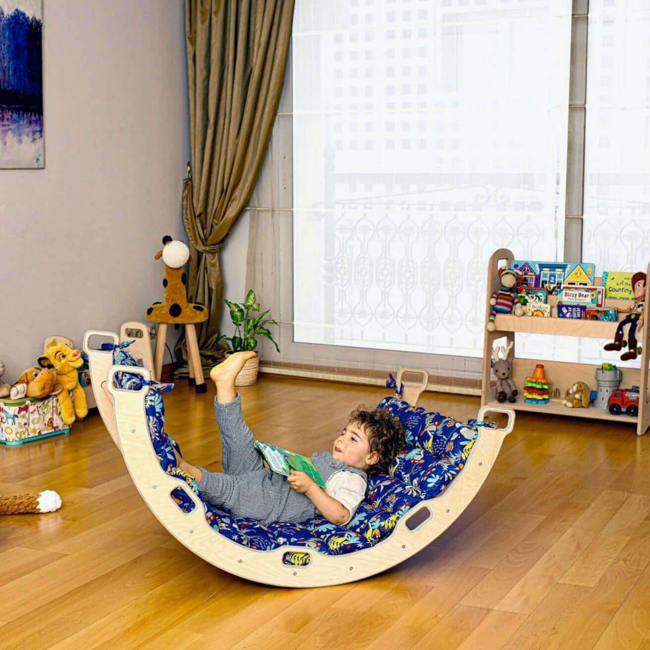 Child playing on Montessori Arch with XL Forest Design Pillow in bright playroom with wooden floor and toys