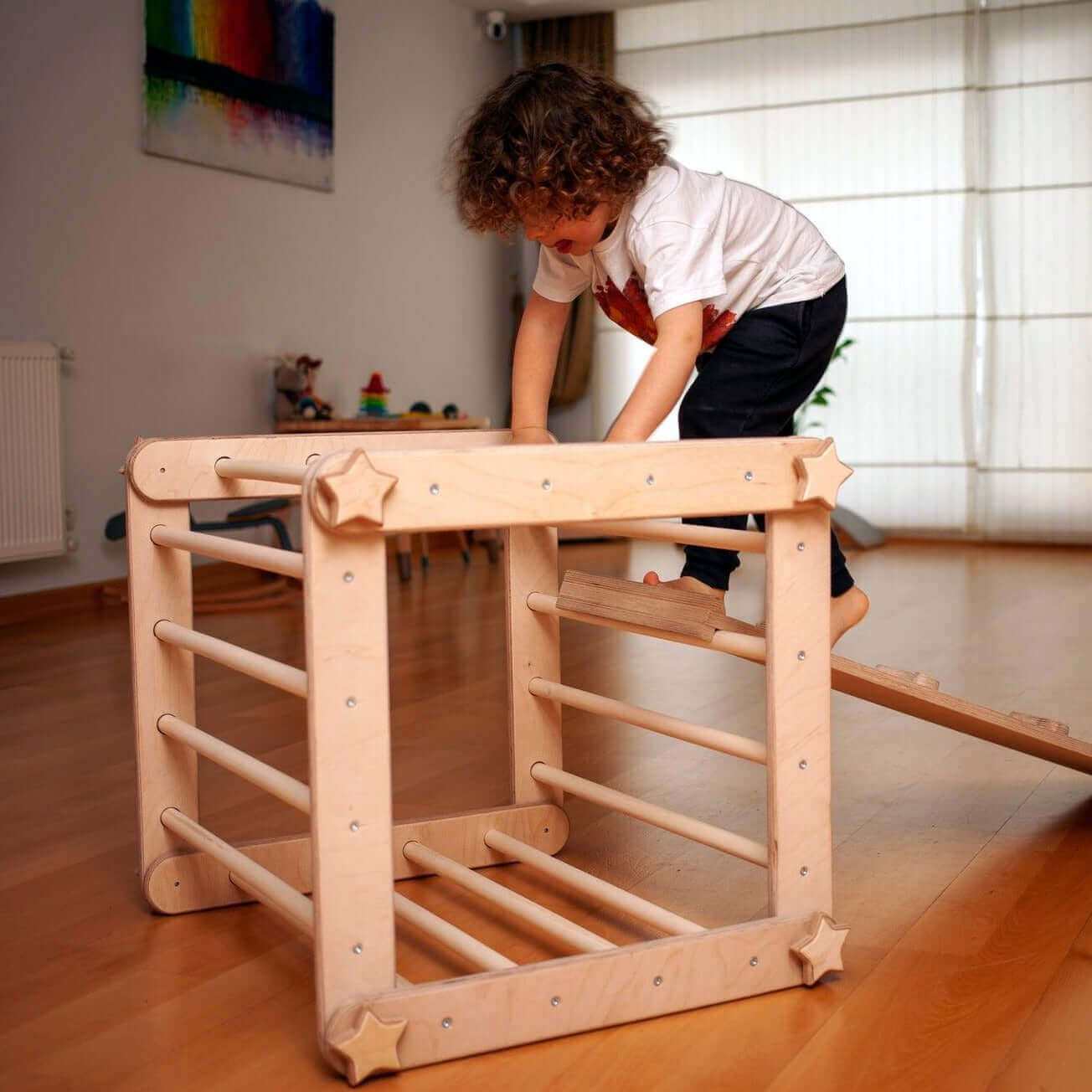 Toddler playing on a wooden Montessori climbing triangle cube with reversible ramp in a bright room