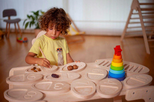 Toddler using wooden tracing board with numbers and wooden pen for learning and play.